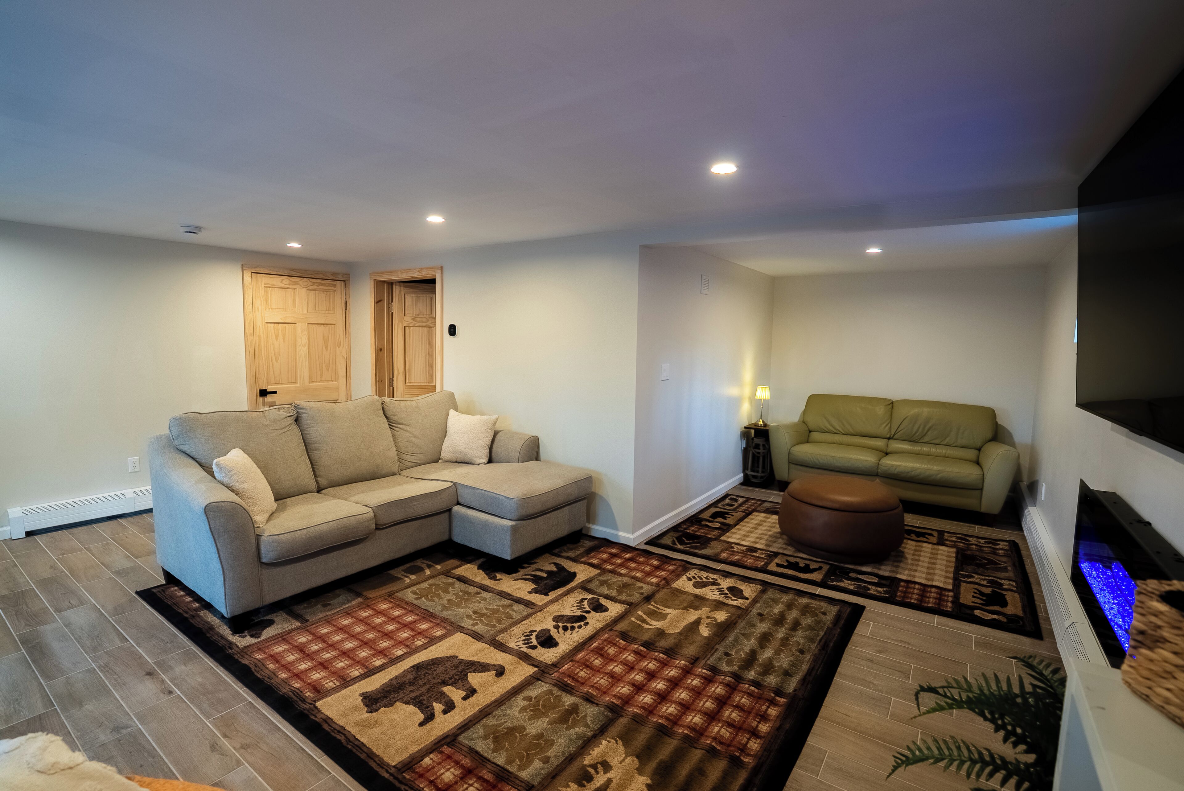 Una sala de estar con un sofá seccional, un sofá verde, una chimenea y un tapete estampado.