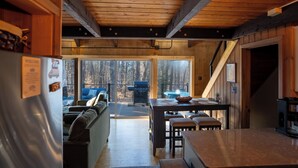 A cabin interior with a kitchen, dining area, and a sliding glass door leading to an outdoor deck.