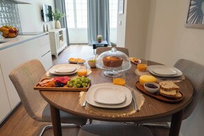 Ein Frühstückstisch mit Obstplatte, Brot und einer mit Stoff bedeckten Kuchen.