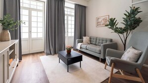Ein Wohnzimmer mit einer Couch, einem Sessel, einem Couchtisch und einer Pflanze.