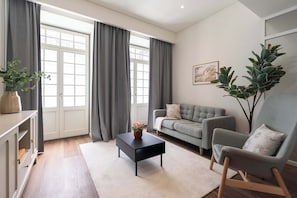 Ein Wohnzimmer mit einer Couch, einem Sessel, einem Couchtisch und einer Pflanze.