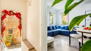 A modern interior with a stone archway, a blue sofa set, and a dining area with a table and chairs. - 2 bedroom Townhouse Located Heart of Kalkan Old Town (Kalkan)