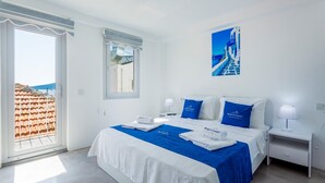 A hotel room with a bed, two bedside tables, a window with a view of a building, and a poster on the wall. - 2 bedroom Townhouse Located Heart of Kalkan Old Town (Kalkan)