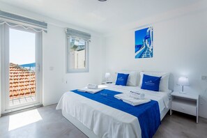 A hotel room with a bed, two bedside tables, a window with a view of a building, and a poster on the wall. - 2 bedroom Townhouse Located Heart of Kalkan Old Town (Kalkan)