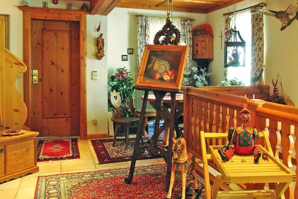A traditional living room with a wooden door, a painting on a stand, a wooden bench, and a rug.