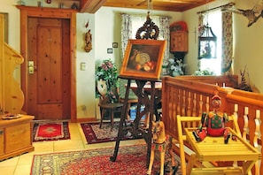 A traditional room with a wooden door, a wooden chair, a small table, and a hanging picture frame.