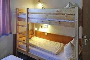 En våningssäng med en stege, ett sängbord och en lampa.