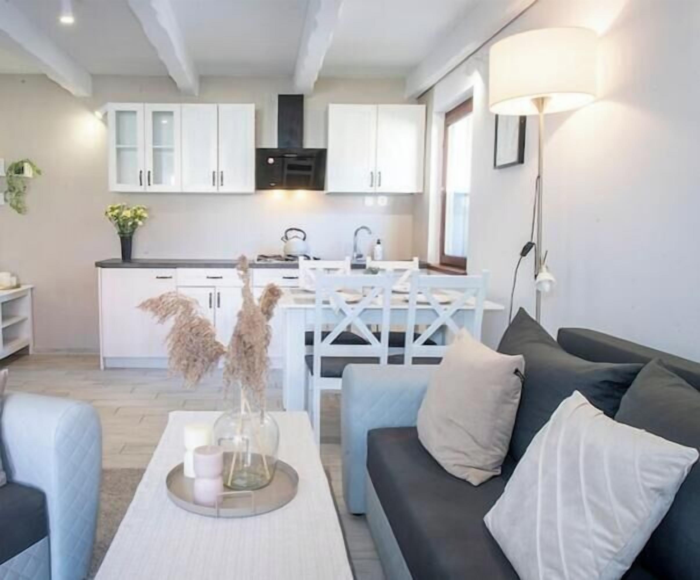 Una sala de estar moderna con un sofá, una mesa de centro y un comedor con una mesa y sillas blancas.