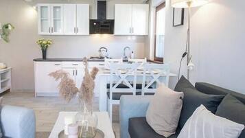 Una sala de estar moderna con un sofá, una mesa de centro y un comedor con una mesa y sillas blancas.