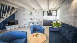 Moderni olohuone, jossa on sohva, nojatuoleja, sohvapöytä, televisio ja portaat.