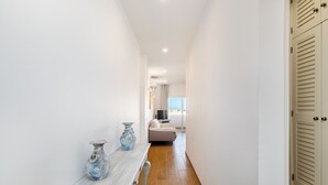 A narrow hallway with a wooden bench, two vases, and a bed in the distance. - Renovated 2BR Lagos w/ Pool & Garage by Soulplaces (Lagos)