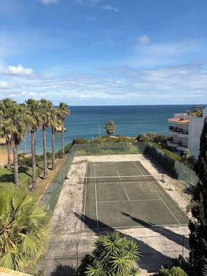 A tennis court with a view of the ocean and palm trees. - Renovated 2BR Lagos w/ Pool & Garage by Soulplaces (Lagos)