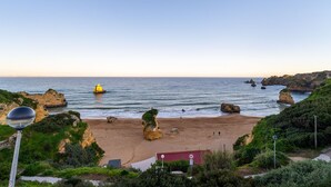 A coastal landscape with a sandy beach, rocky formations, and a clear sky. - Renovated 2BR Lagos w/ Pool & Garage by Soulplaces (Lagos)