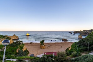 A coastal landscape with a sandy beach, rocky formations, and a clear sky. - Renovated 2BR Lagos w/ Pool & Garage by Soulplaces (Lagos)