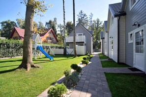 Uma área residencial com um parquinho, um caminho e casas.