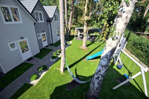 Uma propriedade residencial com gramado bem cuidado, rede, balanço e escorrega.
