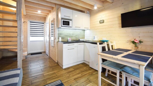 Una cocina compacta con armarios blancos, un microondas y una zona de comedor con mesa y sillas.