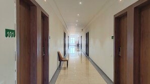A hotel corridor with wooden doors, numbered room signs, and a chair.