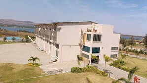 A modern building with a flat roof, multiple windows, and a paved courtyard.