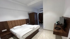 A hotel room with a bed, a TV, a desk, and a wardrobe.