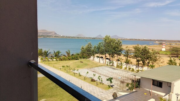 A view from a balcony overlooking a beach, a lighthouse, and distant mountains.