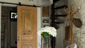 A room with a round table, clear chairs, a wooden door, and a hanging light fixture. - L'Orée du Castel - Gîte at the foot of the castle (Châteauneuf-du-Pape)