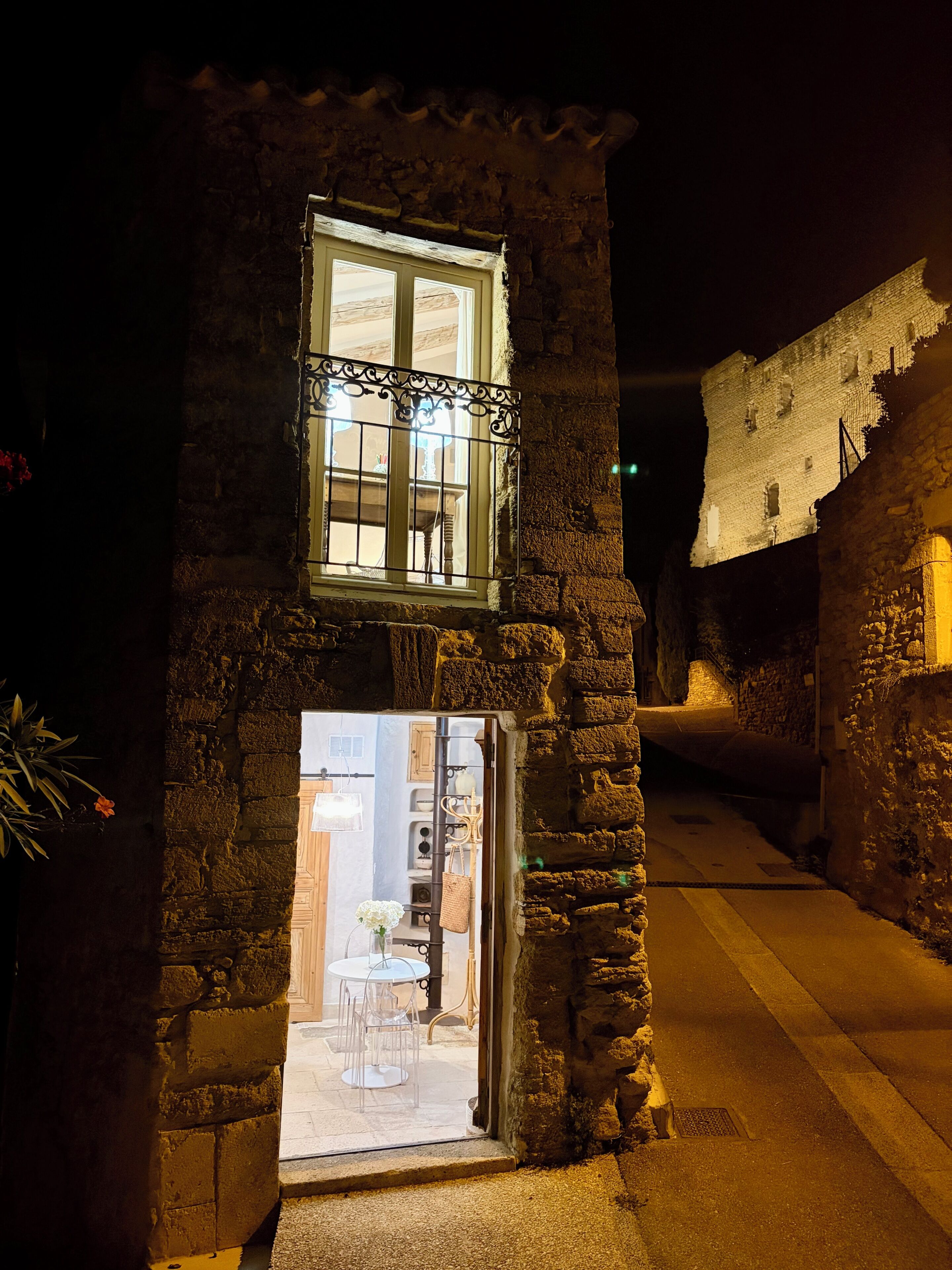 A stone building with a window and a door leading to an interior space with a table and chairs.
