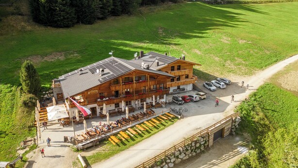 A wooden lodge with a terrace, outdoor seating, and a parking area. - Apartment Ferienwohnungen Grossberghütte (Rio di Pusteria)