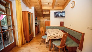 A wooden interior with a dining table, chairs, a television, and a clock on the wall. - Apartment Ferienwohnungen Grossberghütte (Rio di Pusteria)