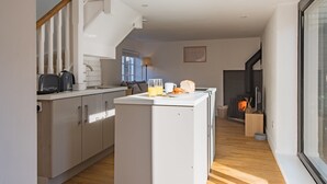 Een moderne keuken met een ingebouwde koelkast, een koffiezetapparaat en een eethoek met een tafel voor twee personen.