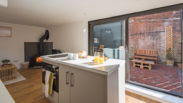 Een moderne keuken met een groot raam, een open haard en een eethoek met een bank.