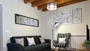 Ein modernes Wohnzimmer mit einer dunklen Couch, einem gestreiften Ohrensessel und Kunstwerken an den Wänden.