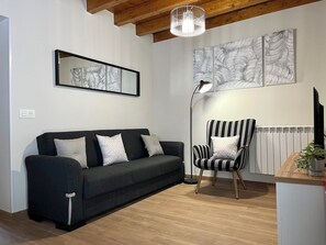 Ein modernes Wohnzimmer mit einer dunklen Couch, einem gestreiften Ohrensessel und Kunstwerken an den Wänden.