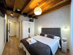A bedroom with a large bed, a wardrobe, a nightstand, and a ceiling light fixture.