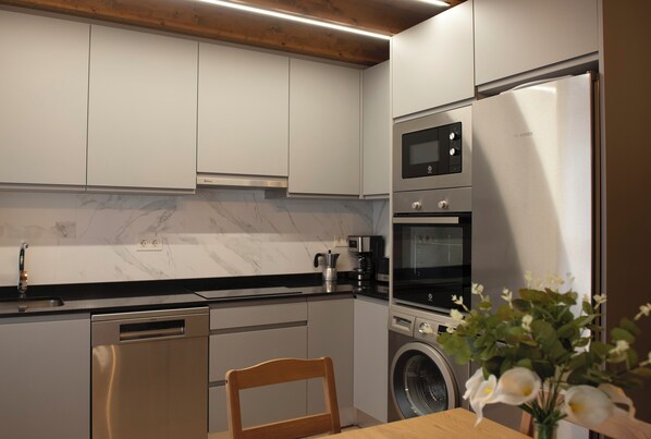 A modern kitchen with white cabinets, a Bosch refrigerator, a built-in oven, and a dishwasher.