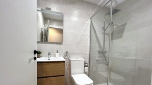 Ein modernes Badezimmer mit einer gläsernen Duschkabine, einem Holzlagerraum und einer weißen Toilette.