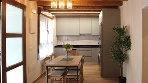 Eine moderne Küche mit Holzschränken, einer Marmorarbeitsplatte und einem Essbereich mit Tisch und Stühlen.
