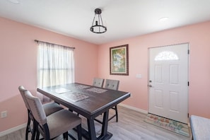 A dining room with a table, chairs, a door, and a window with curtains. - A piece of sunshine (Bradenton)