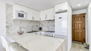 Una cucina moderna con mobili bianchi, un piano di lavoro in marmo ed elettrodomestici integrati.