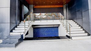 A staircase with a blue garage door, a wooden ceiling, and a metal railing. - Collection O Hotel Evergreen (Faridabad)