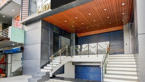 A modern hotel entrance with a staircase, a sign reading 'HOTEL SANDI,' and a blue garage door. - Collection O Hotel Evergreen (Faridabad)
