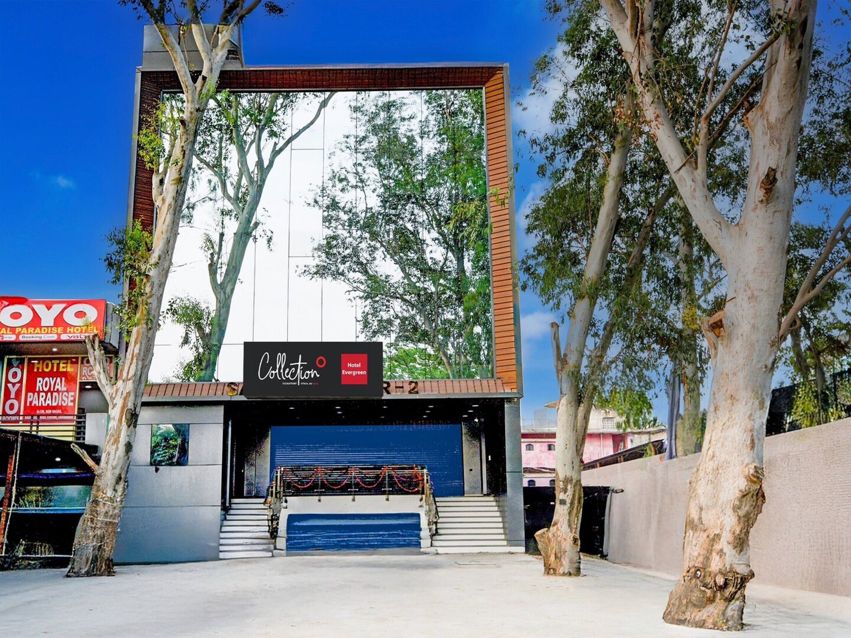 A hotel entrance with a modern facade, a staircase leading up, and a sign for the Royal Paradise Hotel.