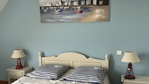 Ein Schlafzimmer mit einem Bett, zwei Nachttischen, einer Lampe, einem Gemälde und einem Holzboden.