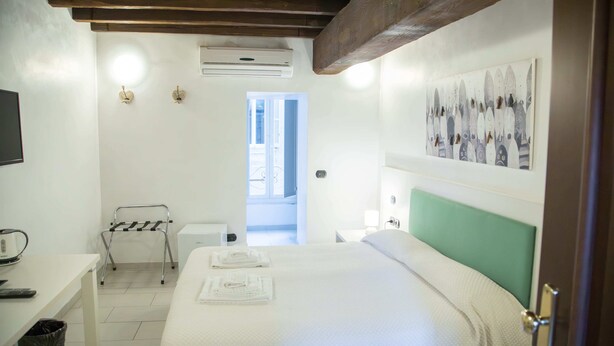 Une chambre d’hôtel avec un lit, un bureau, une chaise, un climatiseur et un tableau au mur.