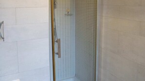 Une salle de bain avec une douche à parois de verre, une baignoire et des toilettes.