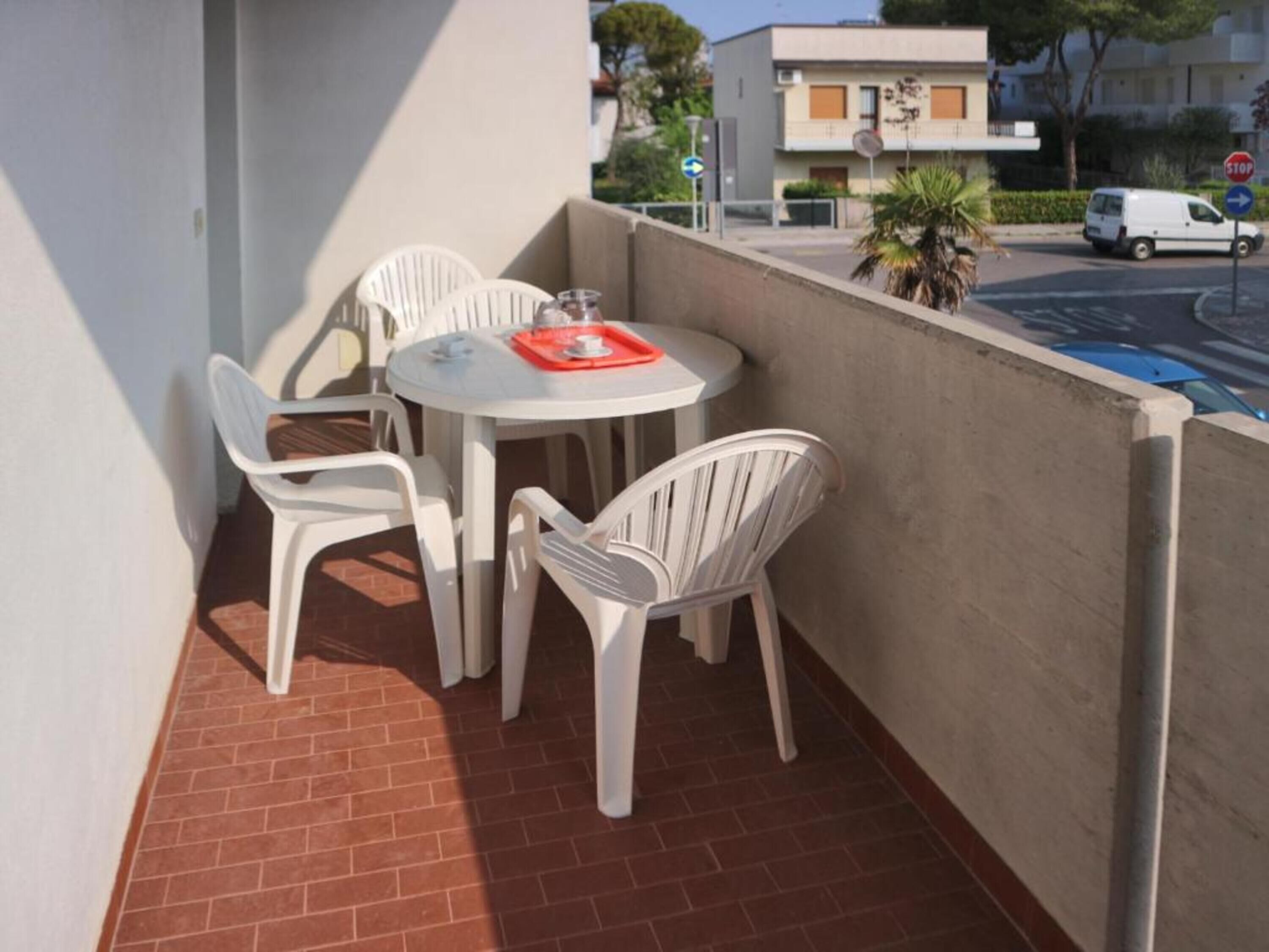 A balcony with a table and chairs, a stop sign, and a building in the background.