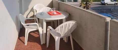 A balcony with a table and chairs, a stop sign, and a building in the background.