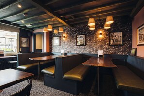 A restaurant interior with booths, tables, and hanging lights.
