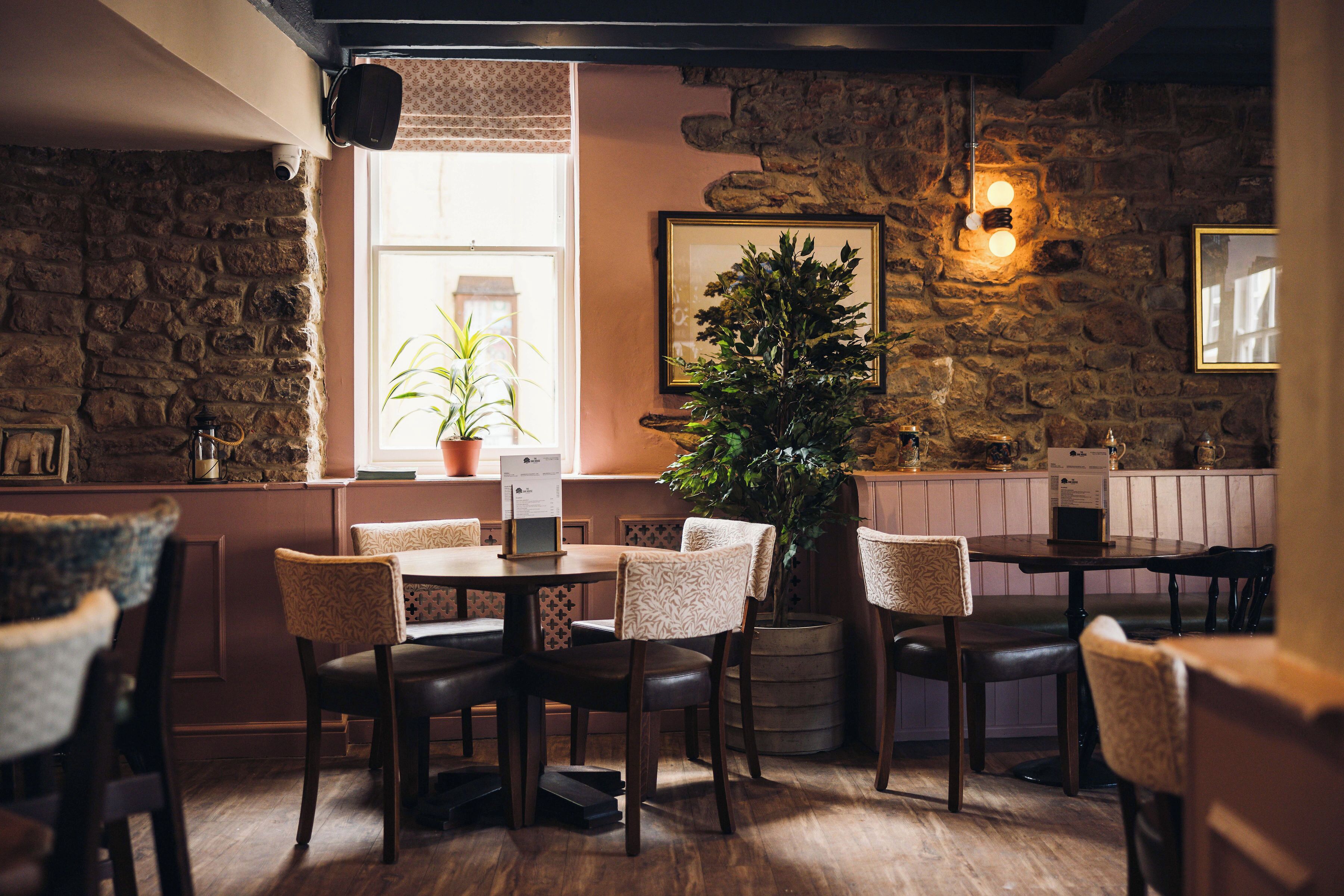 Een restaurantinterieur met stenen muren, houten tafels en stoelen.