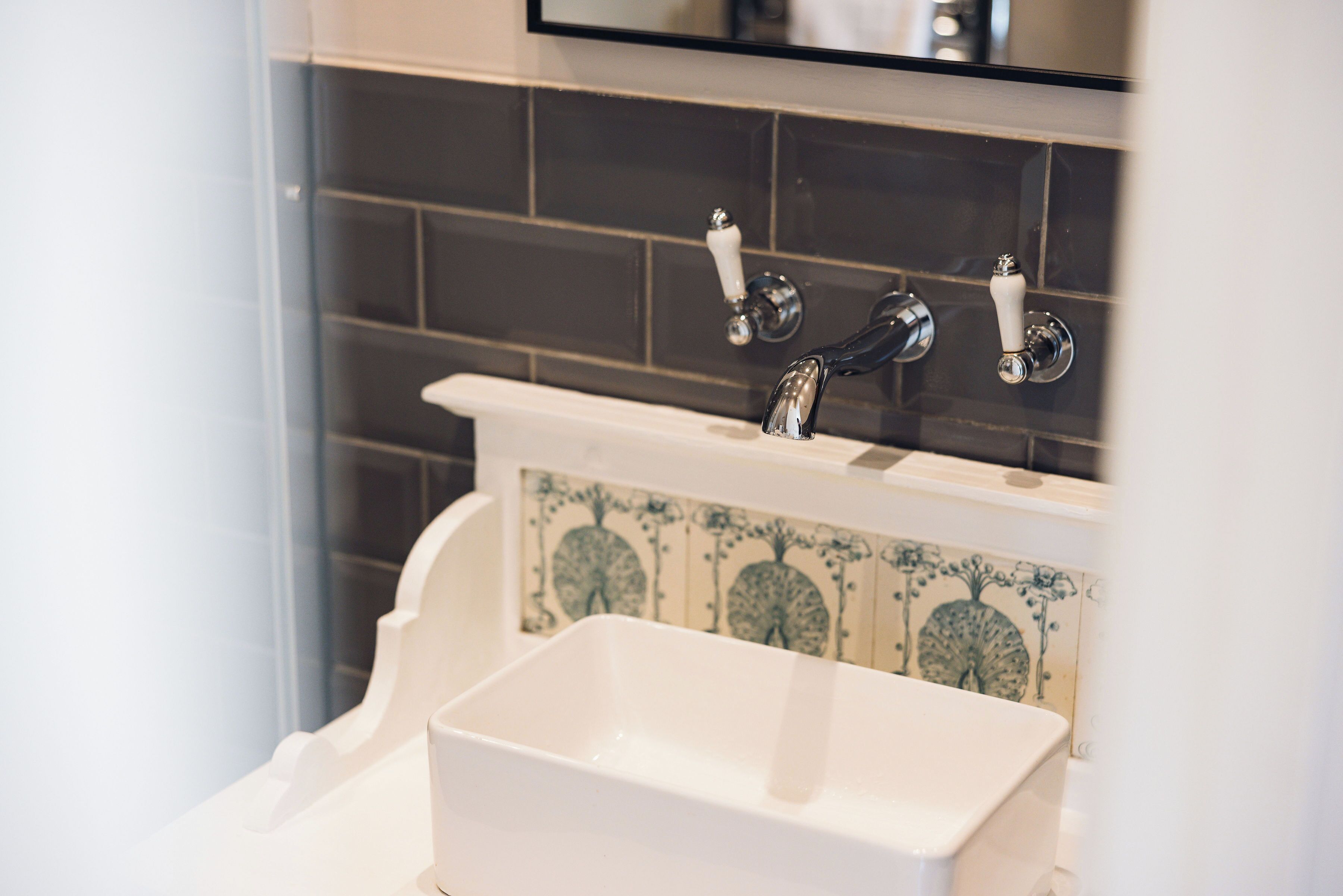 A bathroom with a white sink, a mirror, and a tiled backsplash.